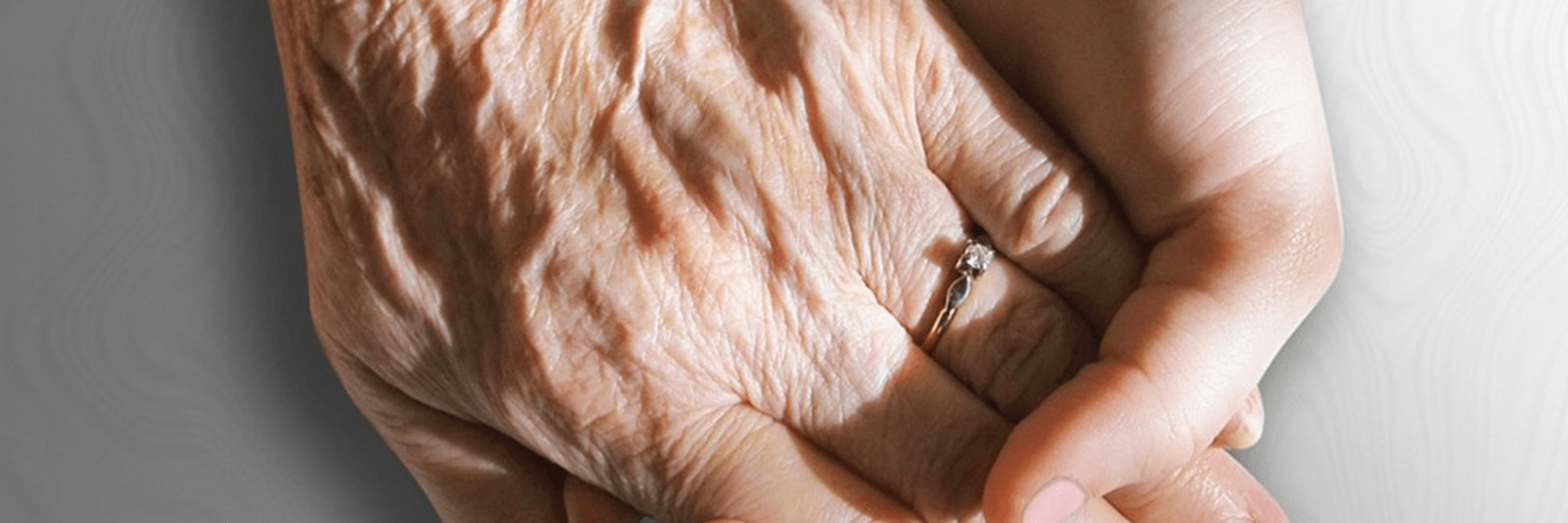 Elderly hand clasped in youthful hand.