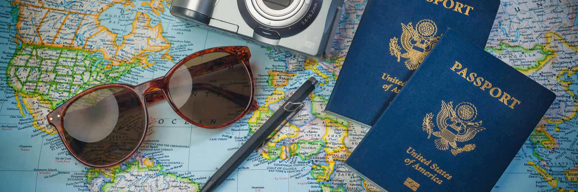 A Map with a pair of sunglasses, camera, and two passports laying on top of it
