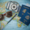 A Map with a pair of sunglasses, camera, and two passports laying on top of it