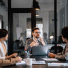 people sitting at a table having a meeting a laptop is open at the end fo the table